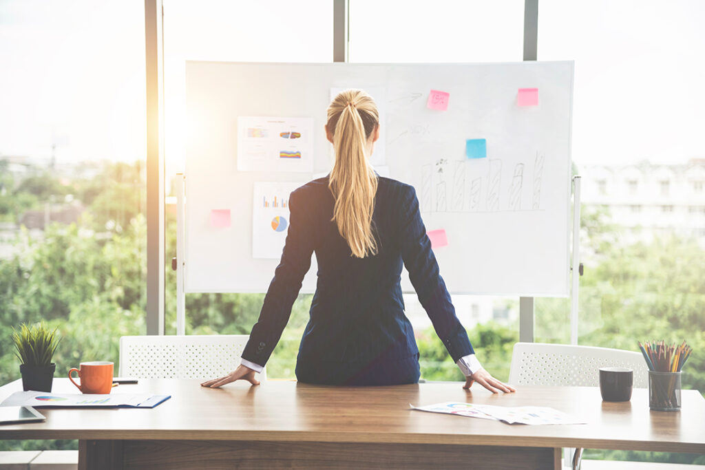 business woman in black blazer looking at vision board