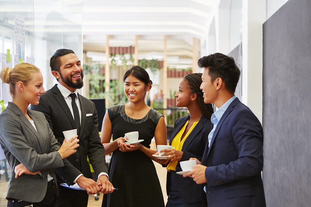 group of men and women holding coffee and engaging in small talk