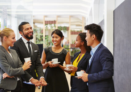group of men and women holding coffee and engaging in small talk