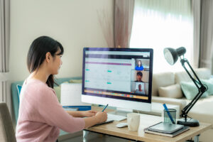 woman in pink shirt sitting at computer on a conference call