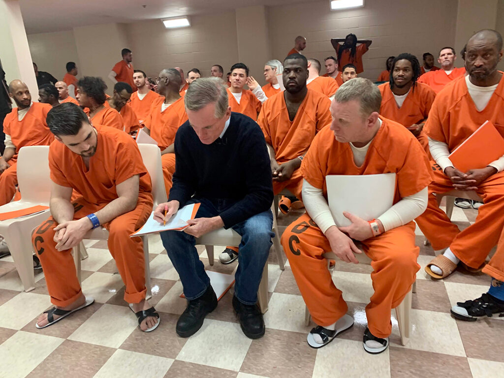 Brian Hamilton teaching inmates in orange jumpsuits