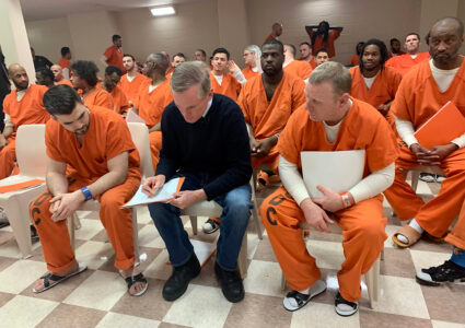 Brian Hamilton teaching inmates in orange jumpsuits