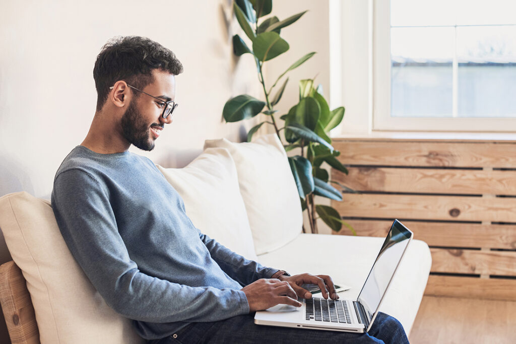 African American man working at laptop on couch