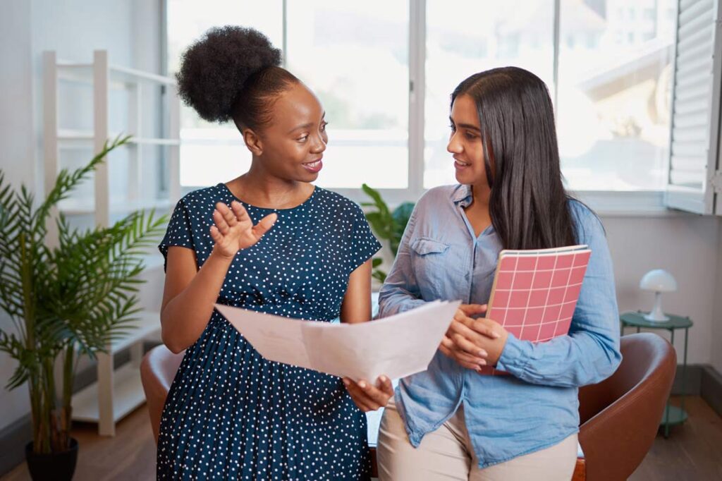 Two businesswomen talking at work learning what a mentor does