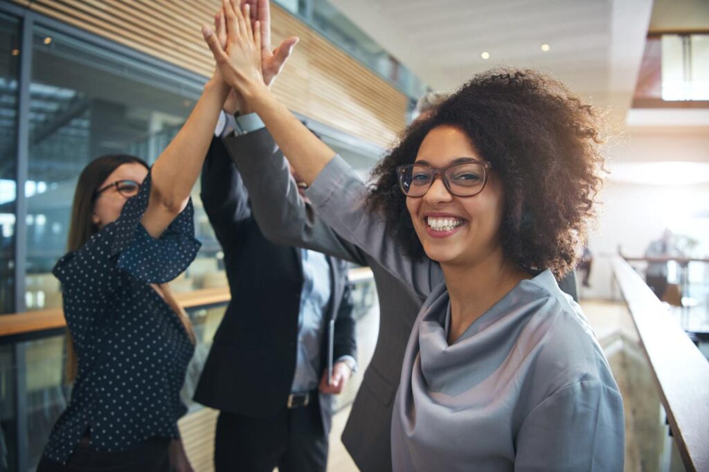 Professional woman high fiving her female colleagues because they've seen through the lies women are told at work