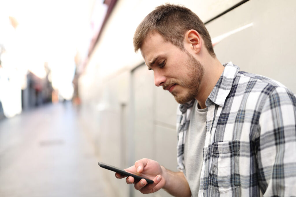 Disappointed man looking at his phone because he's being ghosted after a job interview