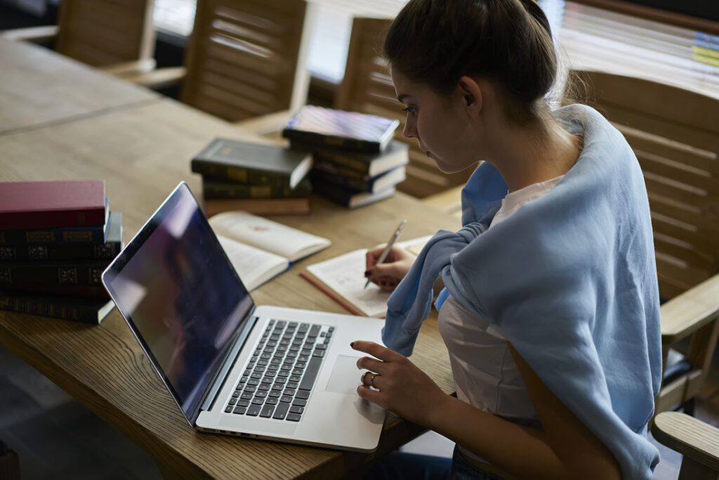 Woman in blue sweater studying at computer