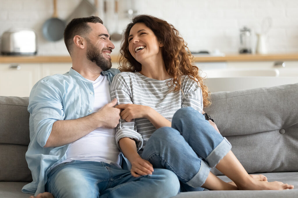 Happy couple sitting on couch smiling