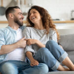 Happy couple sitting on couch smiling