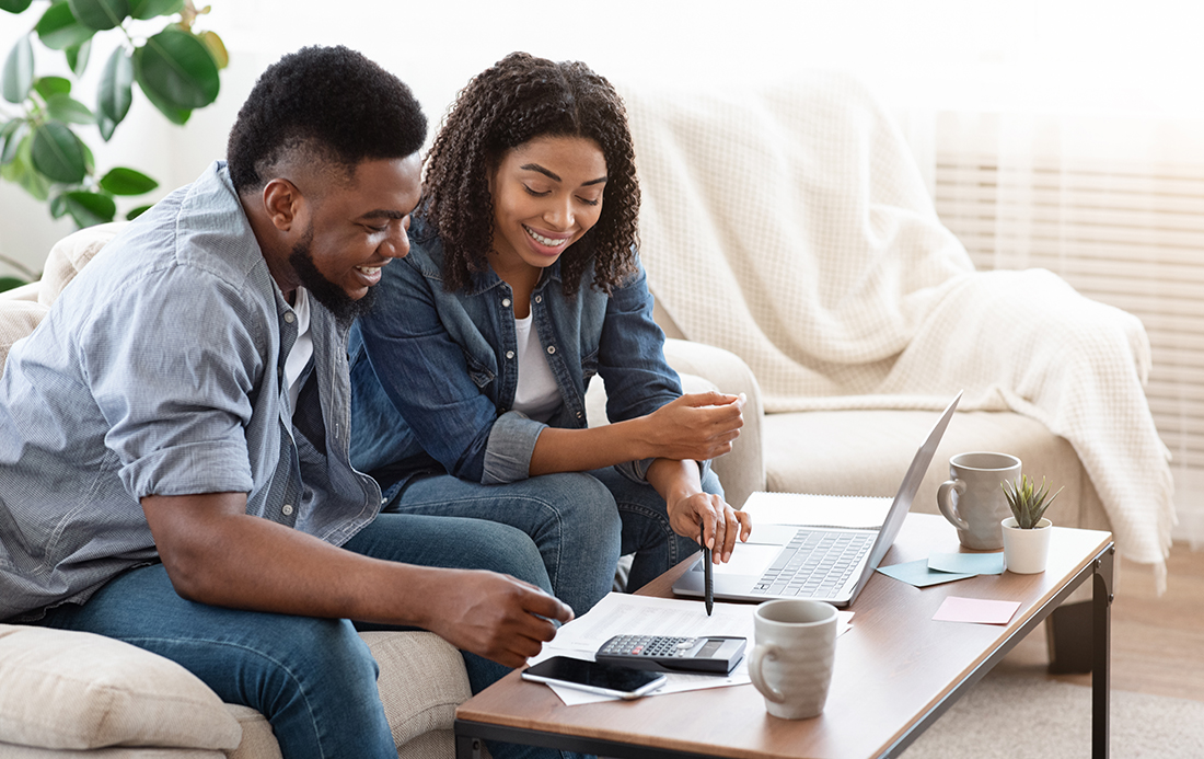 African American couple sitting together on couch creating a budget