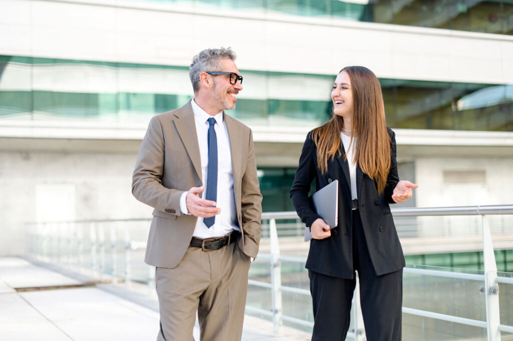 Older male mentor and younger female mentee walking and talking