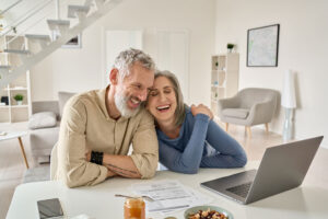 Mature couple smiling using Financial management tools on their laptop