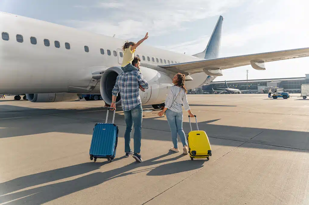 family walking towards airplane with suitcases