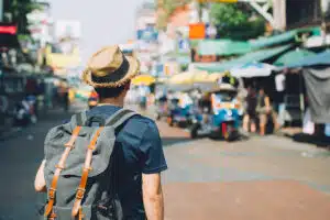 young man with backpack traveling in busy street