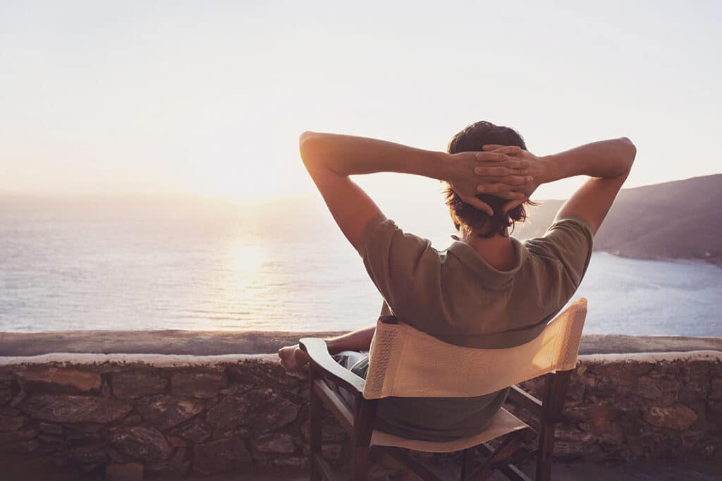 Man sitting in chair looking out at sunset contemplating his midlife edit