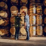 Two Caskx employees inspect whisky barrels. Caskx exemplifies investment advice