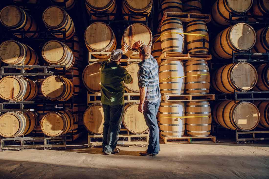 Two Caskx employees inspect whisky barrels. Caskx exemplifies investment advice