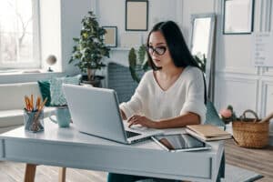 young woman working using laptop while sitting in home office