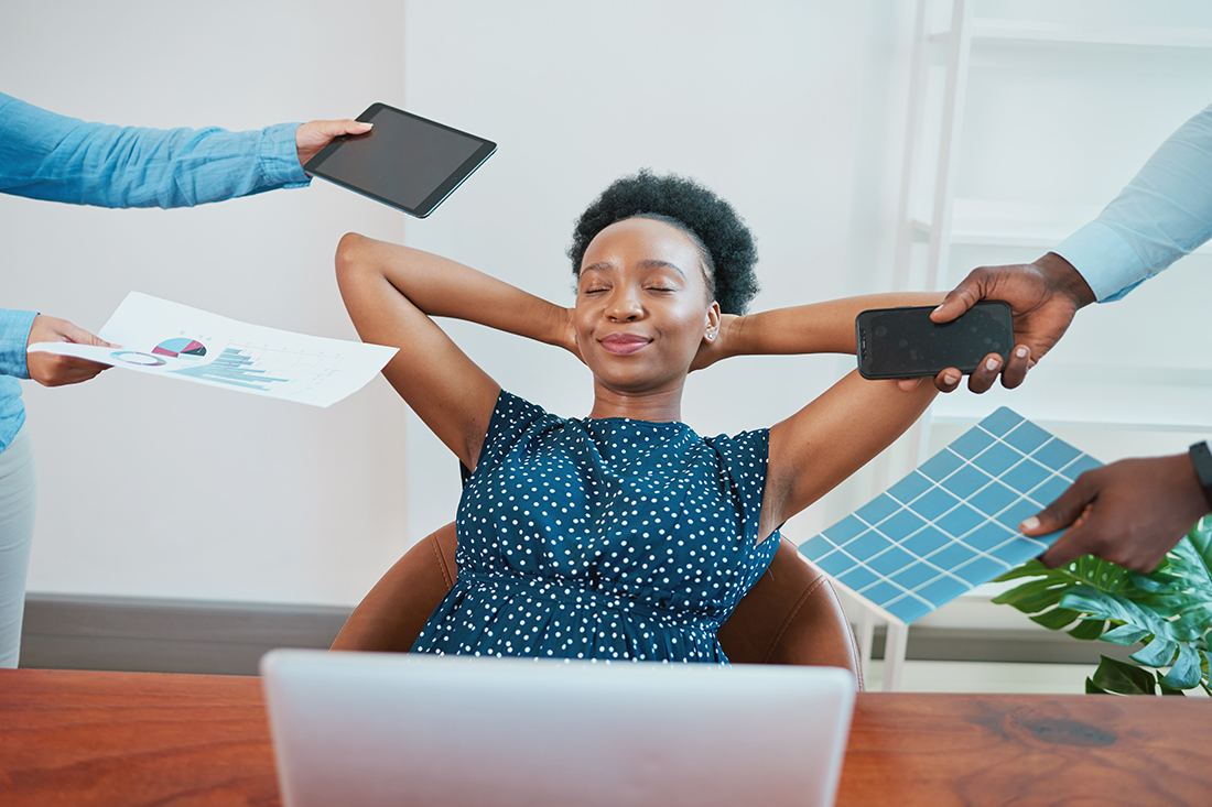Young woman relaxes in her office while coworkers make demands, exercises boundaries