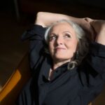 A professionally dressed woman with grey hair and wrinkles.