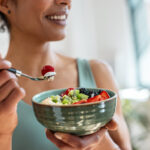 A woman eating a bowl of fruit