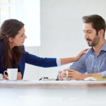women consoling a man at work