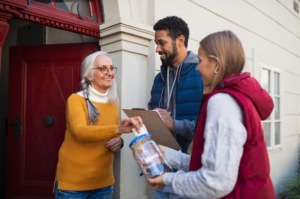 Young door to door fundraisers talking to raising money for charity in street.