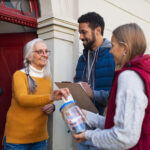 Young door to door fundraisers talking to raising money for charity in street.