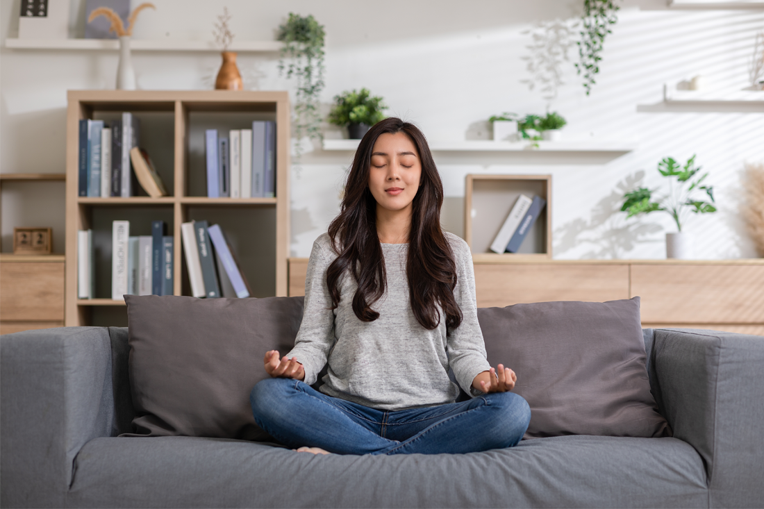 A woman meditates on her couch.