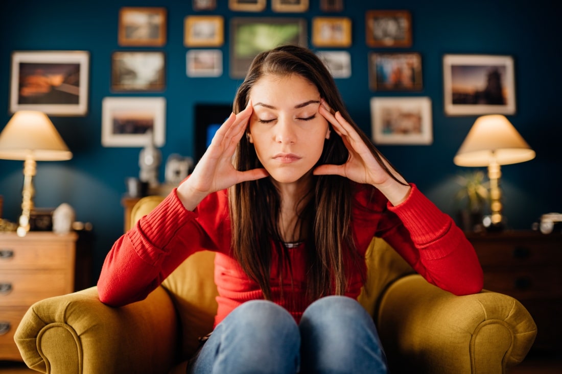 A woman, stressed, has her hands on her face.