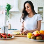 A woman chops fruit on a kitchen island.