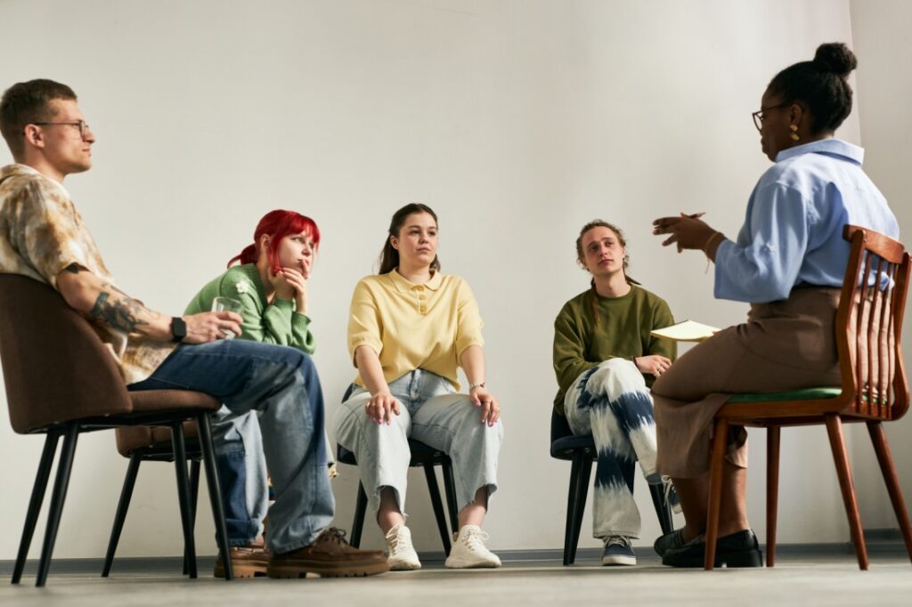 A group therapy session, participants watch the speaker intensely.