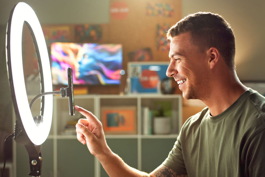 Male Tik Tok creator making content on his phone and smiling