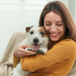 a smiling woman hugging her Jack Russell Terrier dog