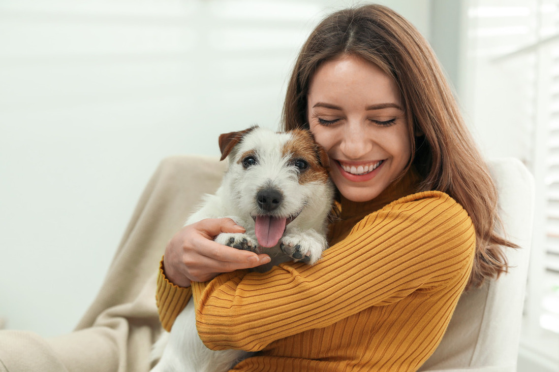 a smiling woman hugging her Jack Russell Terrier dog