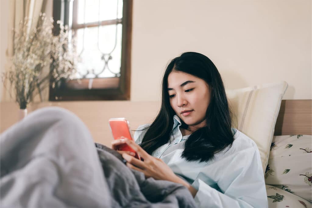 Young woman using smartphone in bed