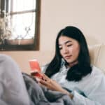 Young woman using smartphone in bed