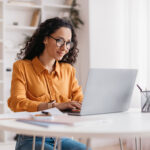 Woman Using Laptop Working Online in Office