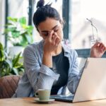 A woman sitting at a desk looking stressed while working