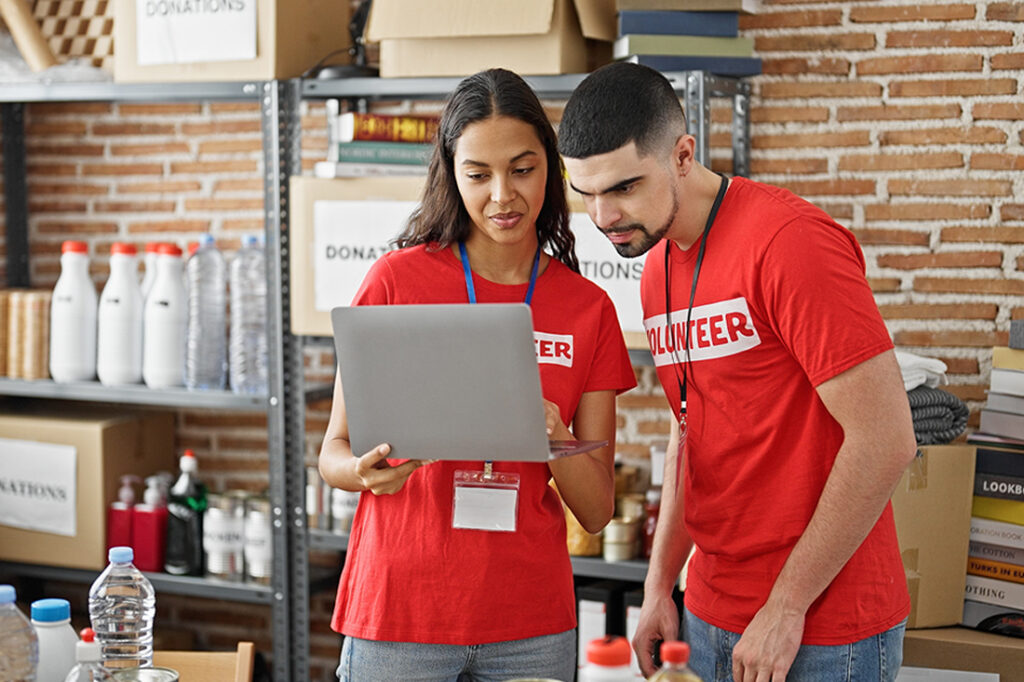 Man and woman volunteers smiling, working on laptop at a fundraiser