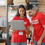 Man and woman volunteers smiling, working on laptop at a fundraiser