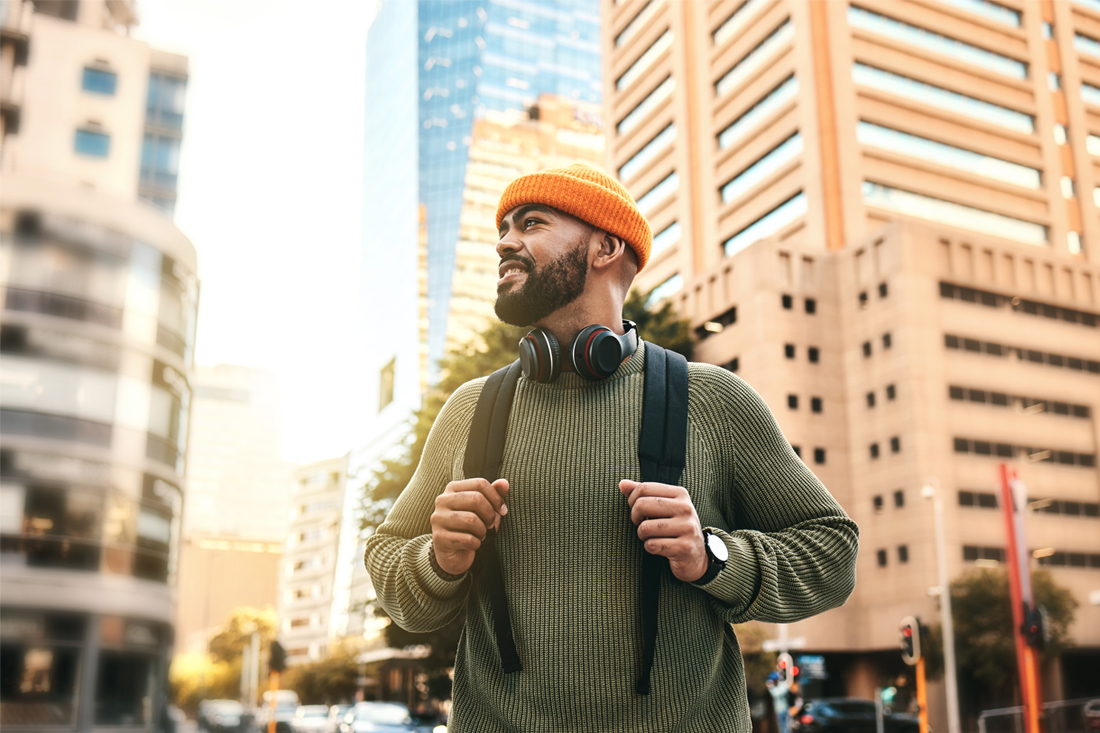 Man in city smiles and wears a backpack while on a miro-retirement trip