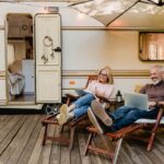 An older couple sits in front of their van.