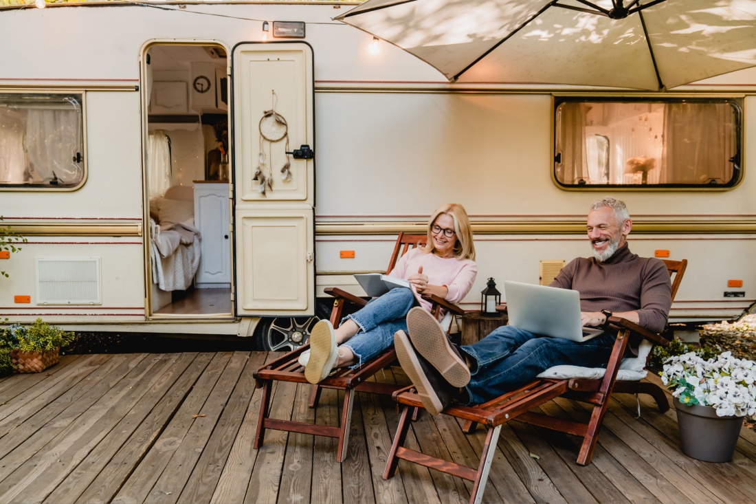 An older couple sits in front of their van.
