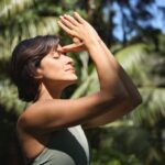 A woman meditates with her thumbs against her forehead.