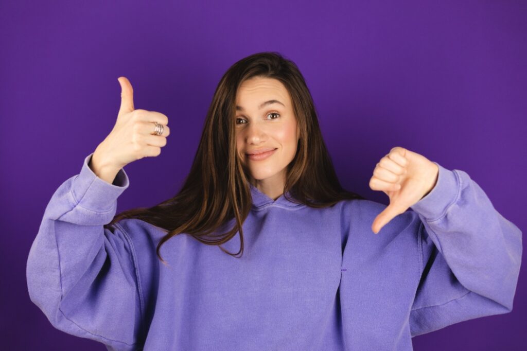A woman makes a thumbs up and a thumbs down sign.