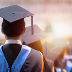 Rear view of university graduates wearing graduation gown and cap in the commencement day