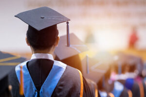 Rear view of university graduates wearing graduation gown and cap in the commencement day