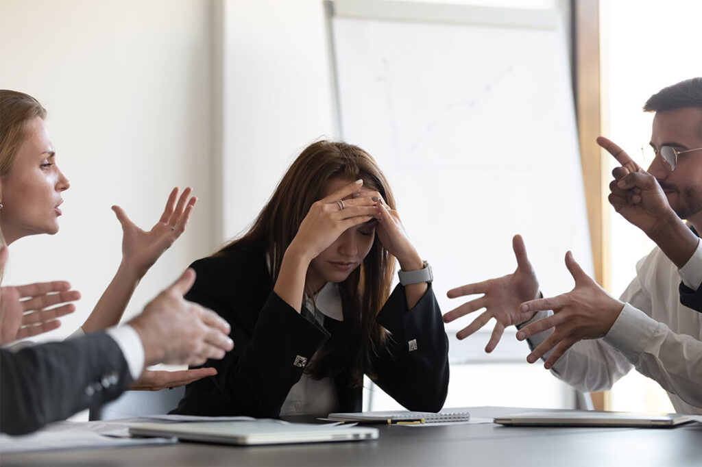 woman at office sitting in the middle of two angry people