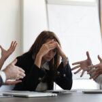 woman at office sitting in the middle of two angry people